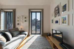 een woonkamer met een bank en een televisie bij Bom-Jardim Trindade in Porto