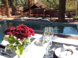 a table with a vase of roses on a table with a pool at Dar Qamar in Agdz