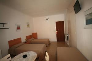 a hotel room with two beds and a television at Hostal Juventus in Portbou