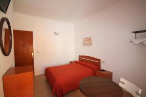 a bedroom with a red bed and a table at Hostal Juventus in Portbou