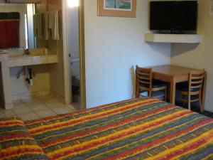 um quarto com uma cama, uma mesa e uma televisão em American Inn em South El Monte