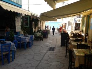Eine Straße mit Tischen und Stühlen und ein Mann, der die Straße entlang geht in der Unterkunft Konstantina Studios in Agios Nikitas