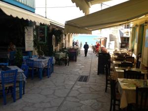 a street with tables and chairs and a man walking down the street at Konstantina Studios in Agios Nikitas