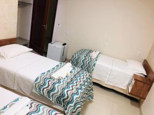 two beds in a hotel room with at Hotel Pousada Real in Sinop