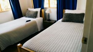 2 camas en una habitación con cortinas azules en Casa de Campo Catapilco, en Catapilco