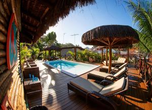 una terraza con sillas, una piscina y una sombrilla en Casa Celestino Residence, en Morro de São Paulo