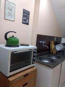 una cocina con microondas y hervidor de agua con té verde. en Colibrí Hostel en Puerto Iguazú