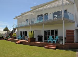 a house with a deck with blue chairs on it at Ulverstone River Edge HolidayApartments in Ulverstone