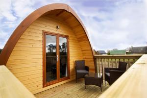 a small wooden house with an archway on a deck at Evelix Pods Dornoch in Dornoch