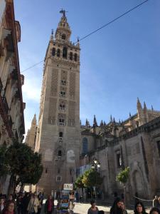 um grande edifício com uma torre de relógio em uma cidade em Apartamentos Flamenco B&B em Sevilha