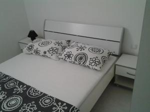 Una cama blanca con almohadas blancas y negras. en Apartments Govic, en Primošten