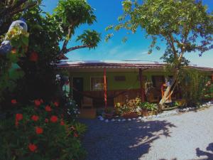 uma pequena casa verde com flores em frente em Hotel Maritza em Puerto Viejo
