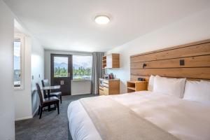 Una habitación de hotel con una cama grande y un escritorio. en Lomond Lodge Motel & Apartments, en Queenstown
