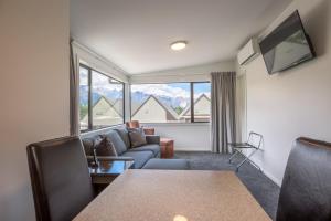 a living room filled with furniture and a tv at Lomond Lodge Motel & Apartments in Queenstown