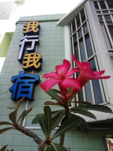 een plant met roze bloemen voor een gebouw bij Wo Xing Wo Su in Hengchun