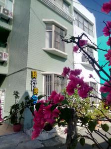 een huis met roze bloemen ervoor bij Wo Xing Wo Su in Hengchun