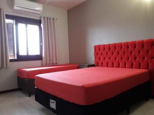 a bedroom with two red beds and a window at Residencial Franca Garopaba in Garopaba