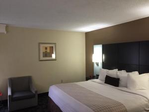 a hotel room with a large bed and a chair at Quality Inn Southside Jacksonville in Orange Park