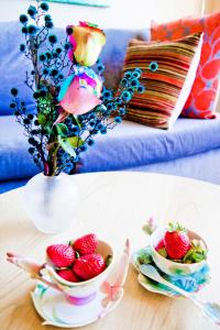 a table with a vase of flowers and a bowl of strawberries at Quest Mascot in Sydney