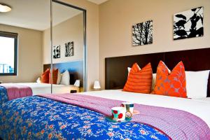 um quarto com uma cama grande com almofadas laranja e azul em Quest Mascot em Sydney