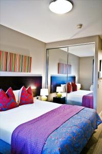 a bedroom with two beds with purple and red pillows at Quest Mascot in Sydney