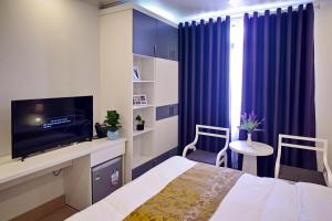 ハイフォンにあるThiên An Hotelのベッドルーム(ベッド1台、テレビ、青いカーテン付)