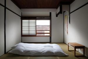 a bedroom with a white bed and a window at Casa OGUMO in Kyoto