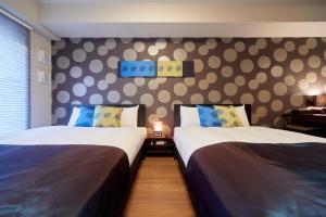 a bedroom with two beds and a wall with polka dots at Hotel Mondonce Kyoto Gojo in Kyoto
