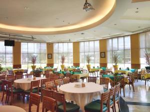 uma sala de jantar com mesas, cadeiras e janelas em Diamond Plaza Hotel em Surat Thani