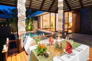 a dining table in a villa with a swimming pool at The Sarojin in Khao Lak