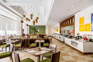 a restaurant with tables and chairs and a kitchen at Kalyan Grand - a business hotel in Vandalūr