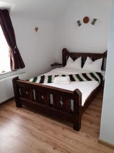 a bedroom with a wooden bed with white sheets at HANUL TENTEA in Săcel