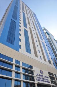 Un edificio alto con un cartel. en Gulf Executive Hotel & Residence Juffair, en Manama