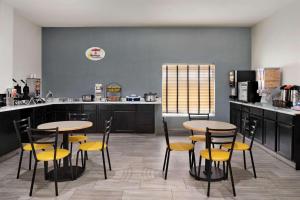 a kitchen with two tables and yellow chairs at Super 8 by Wyndham Des Moines in Des Moines