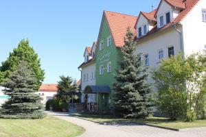 ein grün-weißes Gebäude mit Bäumen davor in der Unterkunft Lindenhof in Thiendorf
