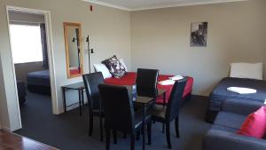 a room with a table and chairs and a bed at Palm Court Motel in Otorohanga