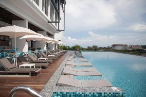 a pool with lounge chairs and umbrellas next to a building at Hard Rock Hotel Desaru Coast in Desaru