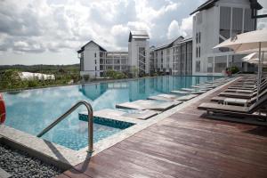 a large swimming pool with chaise lounge chairs next to a building at Hard Rock Hotel Desaru Coast in Desaru