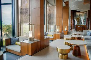 a lobby with tables and chairs and windows at Hard Rock Hotel Desaru Coast in Desaru