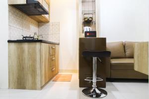 a kitchen with a couch and a bar stool at Well Designed 2BR Green Pramuka City Apartment By Travelio in Jakarta