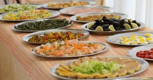 une table avec de nombreuses assiettes de différents types de denrées alimentaires dans l'établissement Hotel Roby, à Riccione