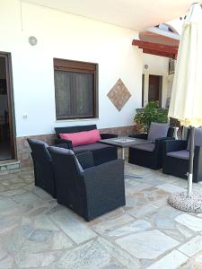a patio with couches and a table and a umbrella at Pelagos Beachfront in Panormos Skopelos