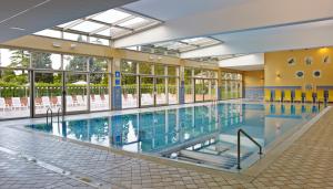 a large swimming pool in a building with windows at Bioenergy Resort Salinera Apartments in Strunjan