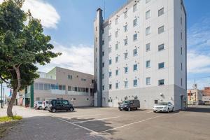 a large white building with cars parked in a parking lot at Hotel Mystays Nayoro in Nayoro