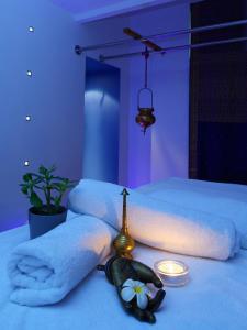 een slaapkamer met 2 bedden, handdoeken en een kaars bij Le Prana - Les Chambres d'Hôtes, Wellness et Centre de soins in Rozérieulles