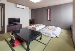 a room with two beds and a table and a tv at Hotel Mystays Nayoro in Nayoro +26 photos