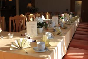 a long table with plates and cups and flowers on it at Lindenhof in Thiendorf