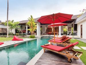 a group of chairs and umbrellas next to a swimming pool at Villa Arte in Seminyak