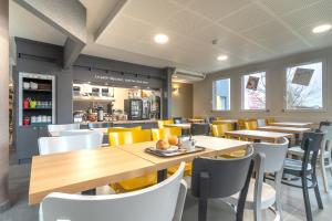 DéolsにあるB&B HOTEL CHATEAUROUX Déolsの木製のテーブルと黄色い椅子のあるレストラン