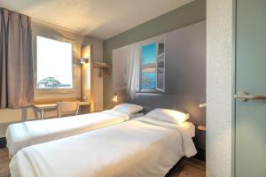 duas camas num quarto de hotel com uma janela em B&B HOTEL CHATEAUROUX Déols em Déols